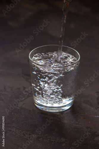Water pouring into a glass, dark background