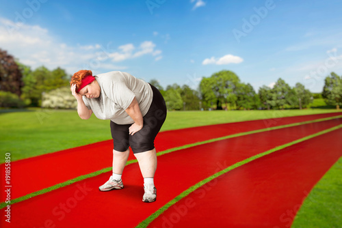 Overweight tired female runner on a jogging track