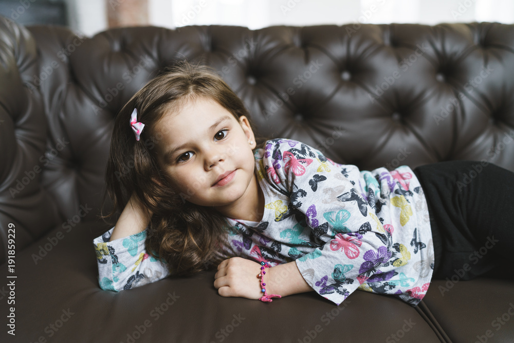 Portrait of a cute preschool girl lying and posing on the sofa Portrait of a cute preschool girl lying and posing on the sofa