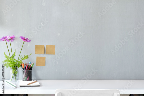 White wood desk with colour pencils, sticky note and flower with copy space. workspace and designer accessories