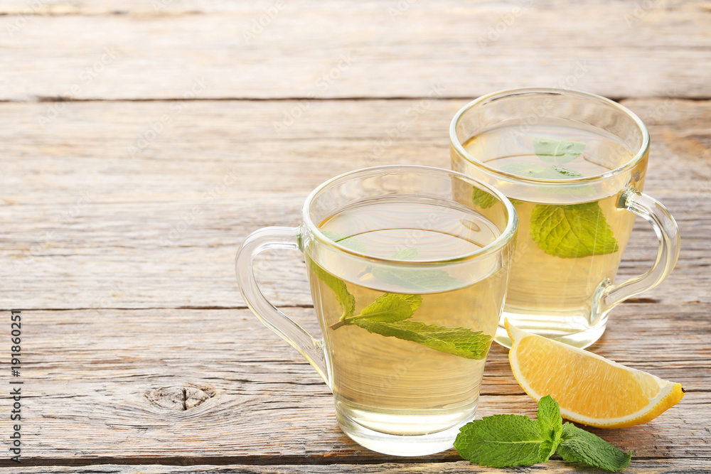 Cup of tea with mint leafs and lemon on wooden table Cup of tea with mint leafs and lemon on wooden table
