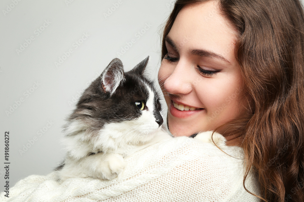 Beautiful young woman holding cat on grey background Beautiful young woman holding cat on grey background