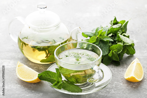 Cup of tea with mint leafs and lemons on wooden table