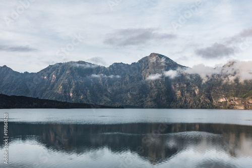 a reflective crater lake is reflecting the mountain peak around them. Rinjani, indonesia