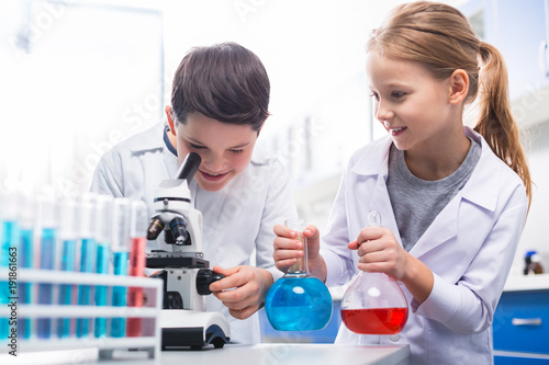 Optimistic happy kids experimenting with microscope