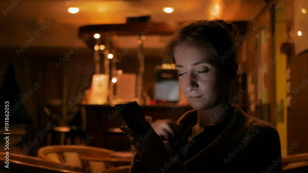 Woman using smartphone in cafe of cruise ship. Evening time, lowlight. Technology and entertainment concept Woman using smartphone in cafe of cruise ship. Evening time, lowlight. Technology and entertainment concept