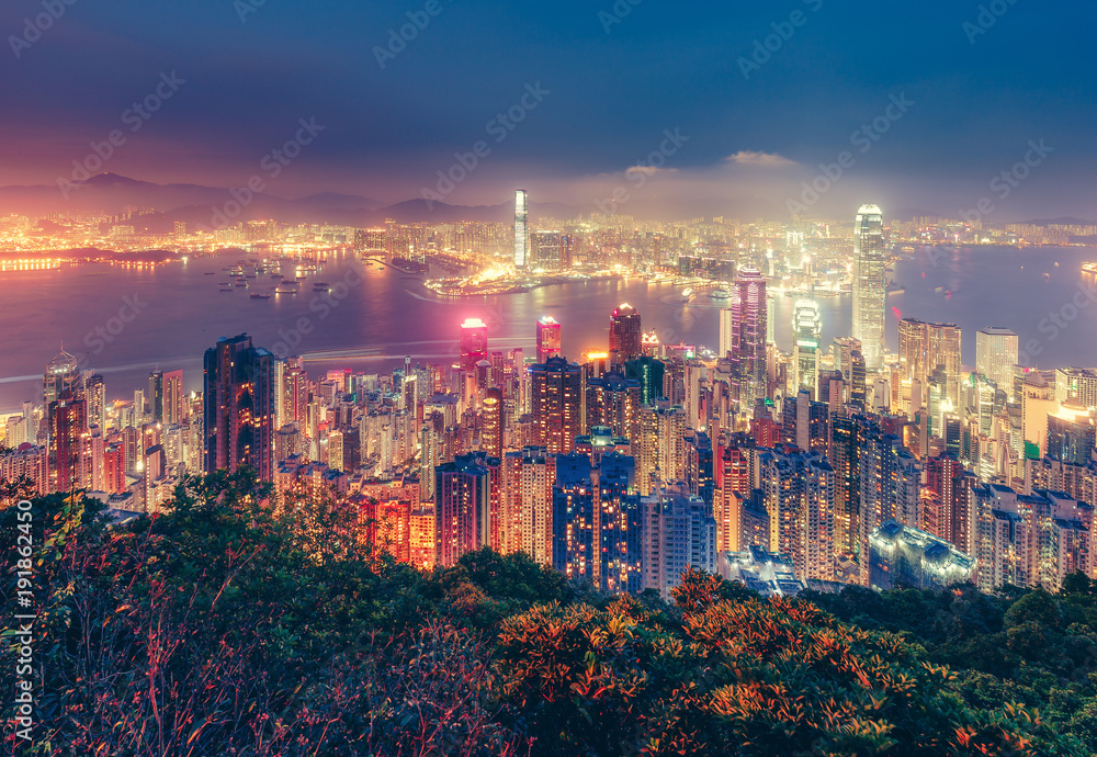 Fototapeta premium Sceniczny widok nad Hong Kong wyspą, Chiny nocą. Wielokolorowa nocna linia horyzontu z oświetlonymi wieżowcami widzianymi z Victoria Peak