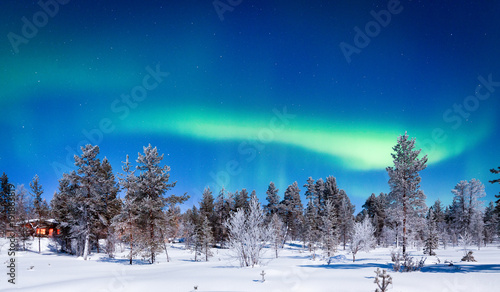 Aurora Borealis over winter wonderland scenery in Scandinavia