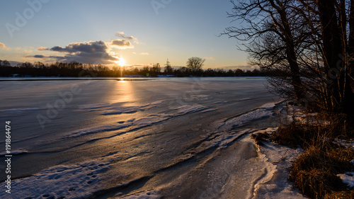 colorful winter sunset on frozen river ice