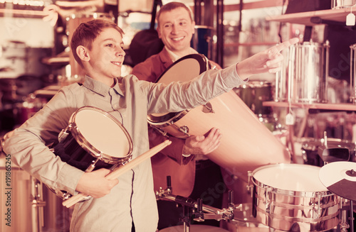 teenager and father deciding on ethnic drum in musical shop