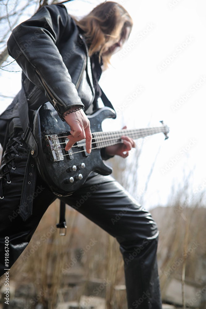 Fototapeta premium Rock guitarist on the steps. A musician with a bass guitar in a 