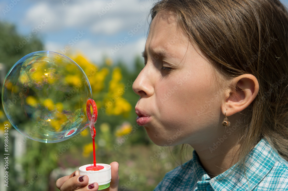 A girl in a plaid shirt is playing with soap bubbles A girl in a plaid shirt is playing with soap bubbles