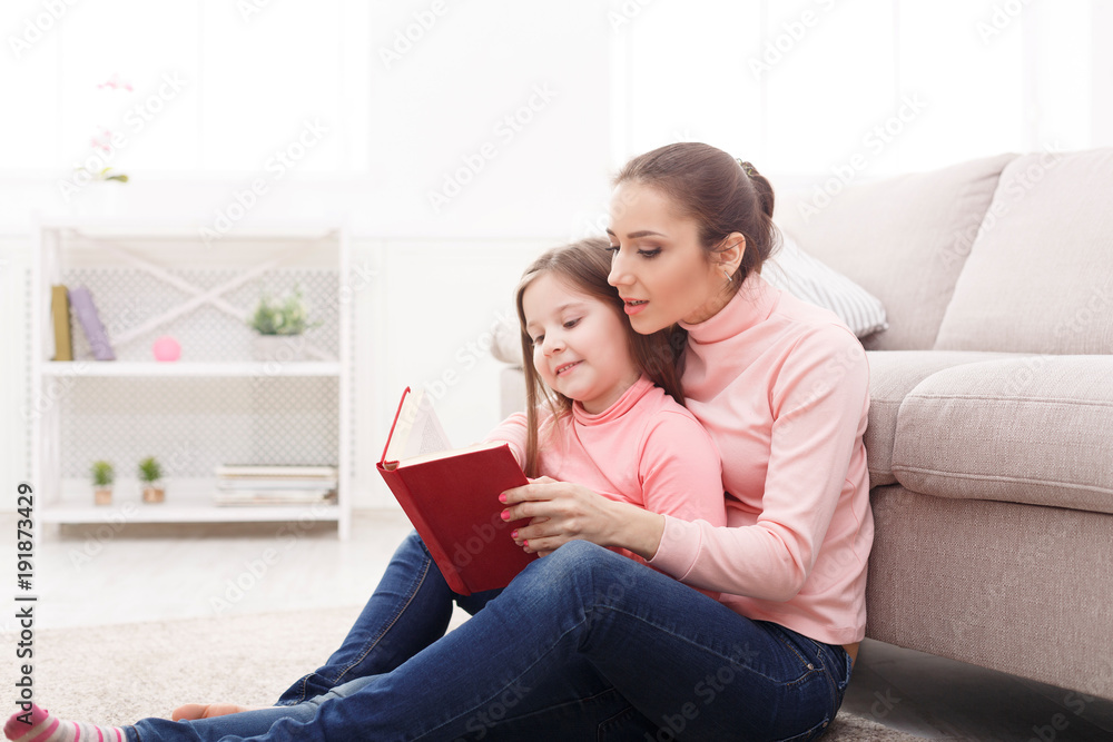 Little girl and her mom reading book at home Little girl and her mom reading book at home