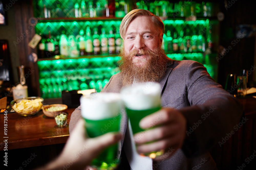 Happy bearded man toasting with his friend in irish pub on Saint Patrick day Happy bearded man toasting with his friend in irish pub on Saint Patrick day