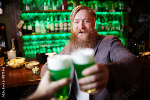 Happy bearded man toasting with his friend in irish pub on Saint Patrick day