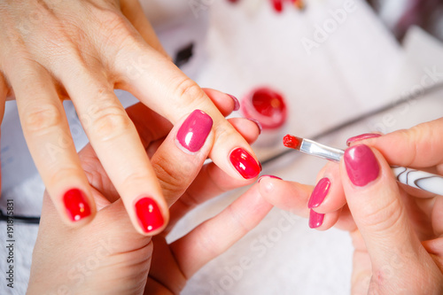Manicure in progress - Beautiful manicured woman's nails with red nail polish. The industry of beauty and nail care, beauty salons