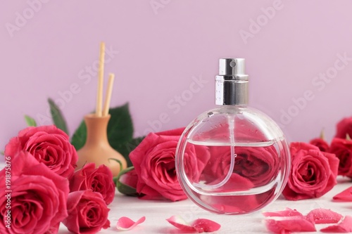 Feminine perfume spray bottle with pink roses flowers and incense sticks. Lilac tones background, aromatherapy set photo