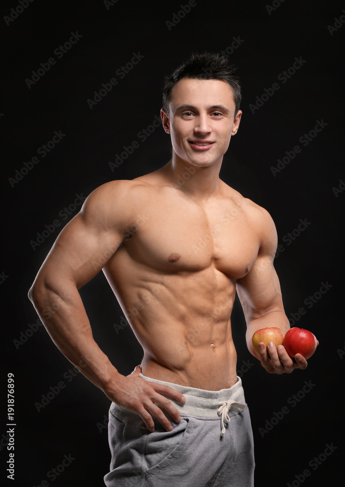 Handsome muscular young man with apples on black background Handsome muscular young man with apples on black background