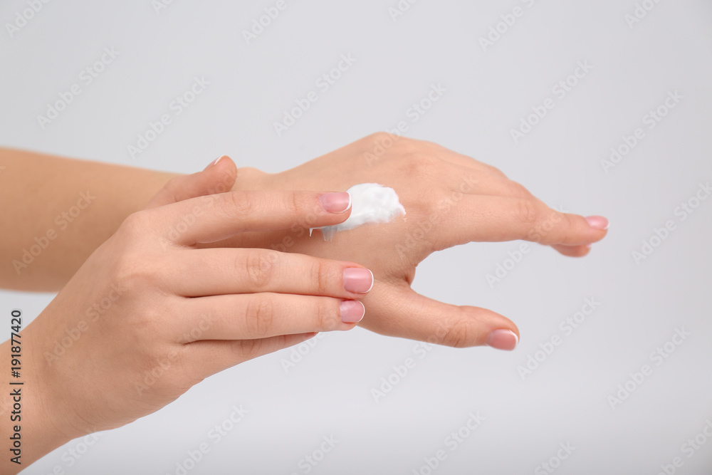 Woman applying body cream on light background Woman applying body cream on light background