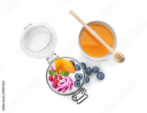 Yogurt with fruits in jar and bowl of honey on white background