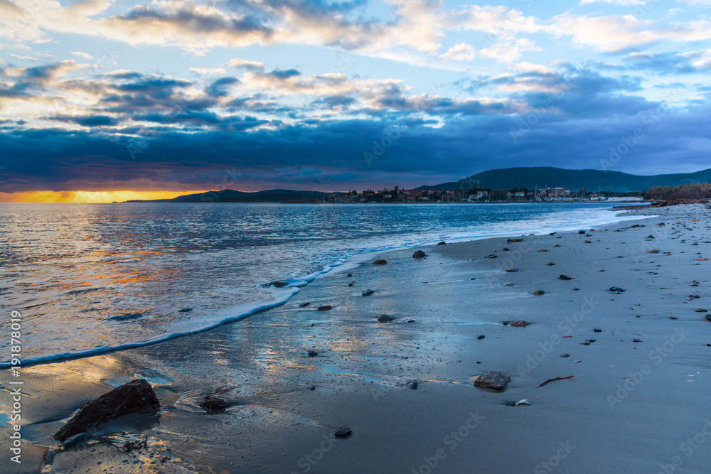 Rocks and sand in Alghero shore at sunset