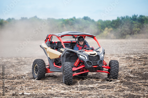 Smiling man at the wheel of quad bike standing in the field