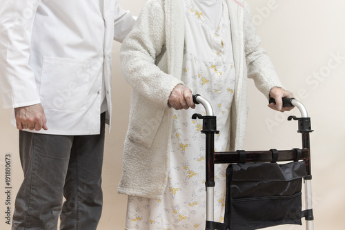 10. Pielęgniarz pomaga iść starej kobiecie trzymającej się chodzika.