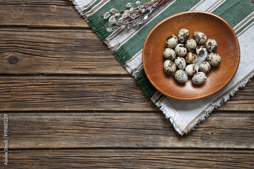 Quail eggs on a plate. Easter serving of the festive table. Top view, space for your text on a rustic wooden background