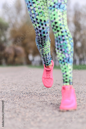 a young girl goes in for sports in the fresh air . Sports clothing pink color . listening to music on headphones and runs