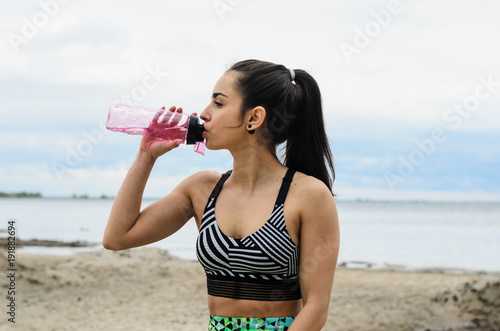 a young girl goes in for sports in the fresh air . Sports clothing pink color . drink water