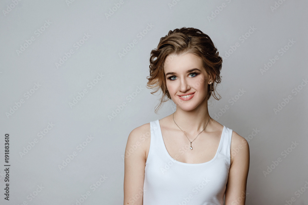 Portrait of the young smiling European girl in a white undershirt on a white background. Natural beauty, the shining skin, white teeth.Body language and emotions. Portrait of the young smiling European girl in a white undershirt on a white background. Natural beauty, the shining skin, white teeth.Body language and emotions.