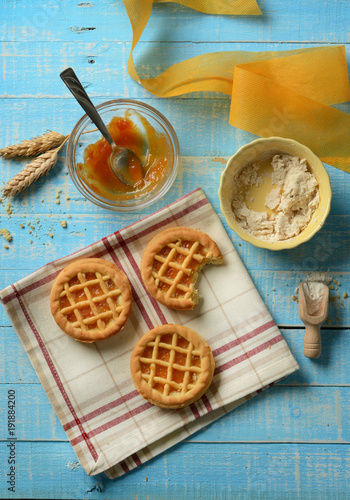 small pies with ingredients around on light blue table
