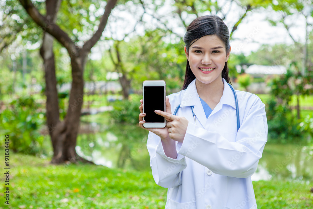 Portrait of a confident female doctor showing mobile phone in garden outdoor Portrait of a confident female doctor showing mobile phone in garden outdoor