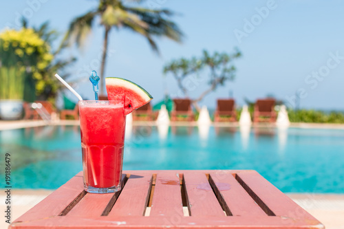 Healthy concept, Water melon smoothie on a wood table with swimming pool and blue sky background.