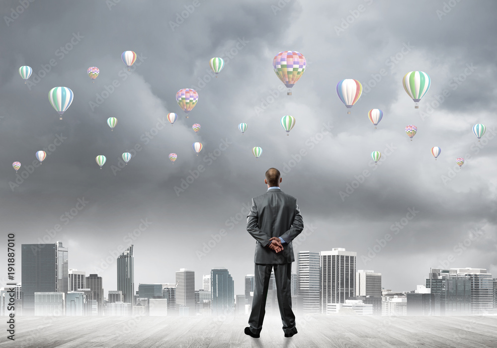 Motivation and inspiration concept with modern cityscape and businessman observing it Motivation and inspiration concept with modern cityscape and businessman observing it