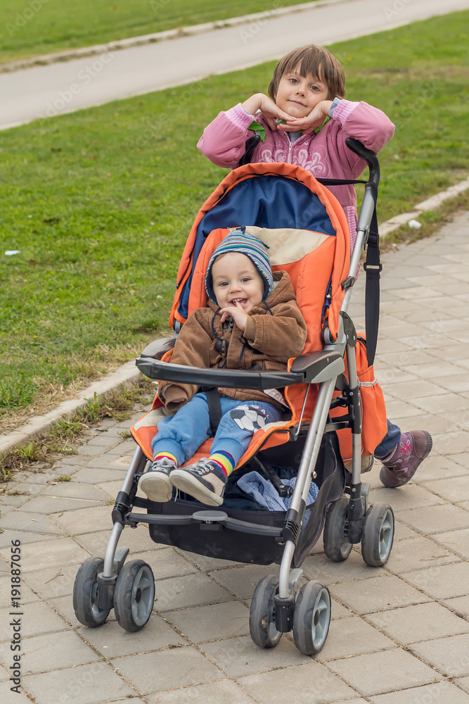 sister walking with young brother in stroller sister walking with young brother in stroller