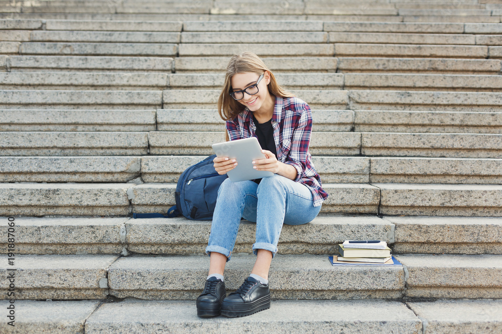 Happy young woman using digital tablet outdoors
