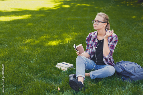 Young woman listening to music on grass outdoors