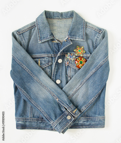 Jeans denim woman jacket with vintage brooches on white background. Fashion outfit