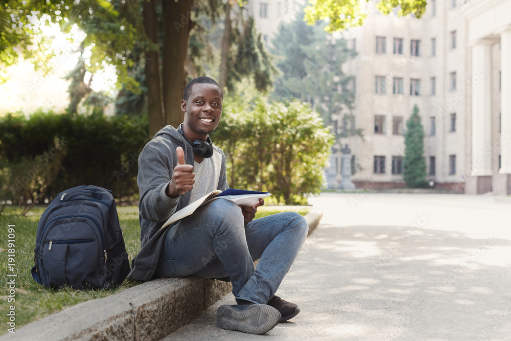 African-american student sitting with notebook in university campus African-american student sitting with notebook in university campus