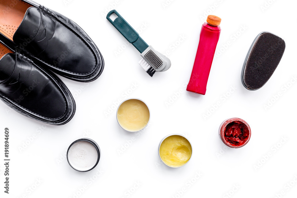 Shoe care products. Leather men shoes, shoe polish, brushes, wax on white background top view Shoe care products. Leather men shoes, shoe polish, brushes, wax on white background top view