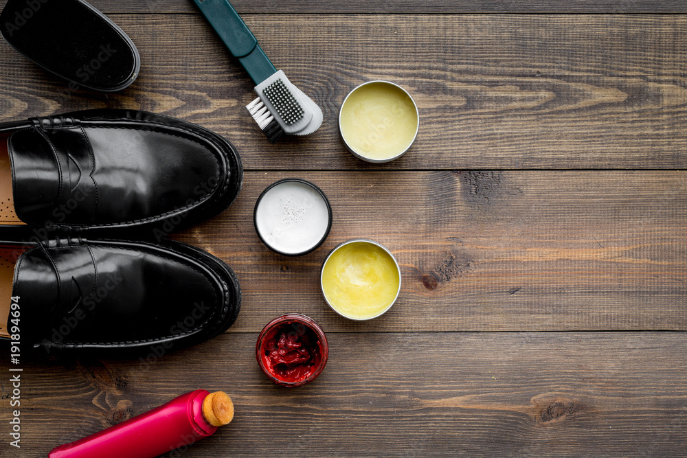 Shoe polish, brushes, wax near black shiny leather shoes on dark wooden background top view copy space Shoe polish, brushes, wax near black shiny leather shoes on dark wooden background top view copy space