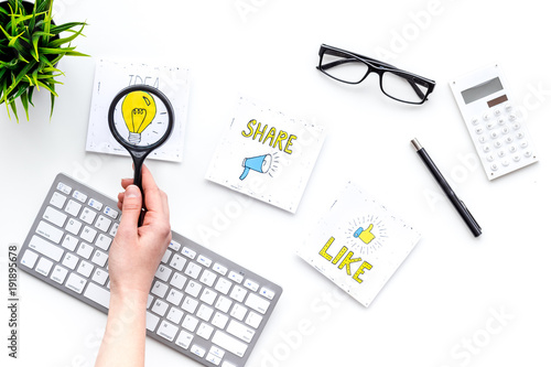 Digital marketing. Work desk of marketing specialist with social media icons and symbols. Hand with magnifiger on white background top view copy space photo