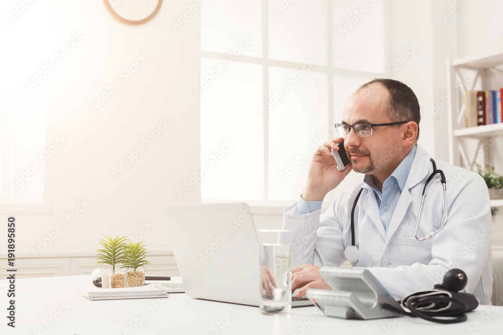 Handsome doctor talking on the phone with his patient