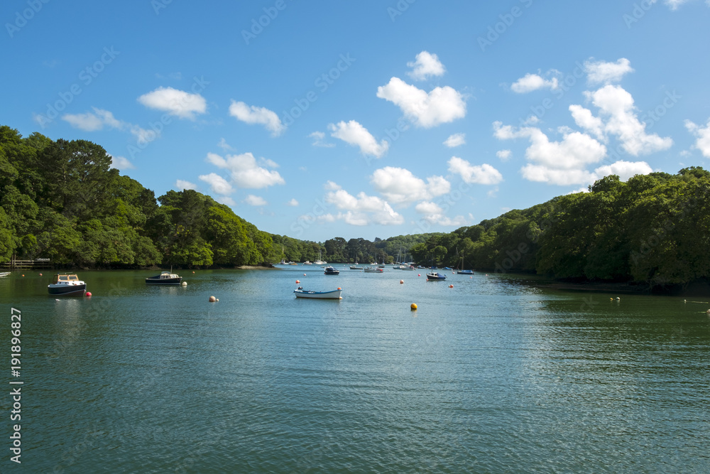 Early summer afternoon sunshine on idyllic small boat moorings in the Helford Estuary at Port Navas, Cornwall, UK