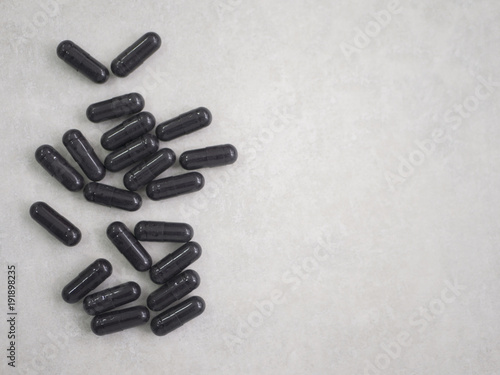 many black pills on grey white background, in left side