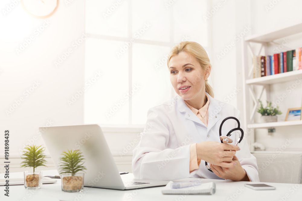 Portrait of doctor with stethoscope sitting at the desktop