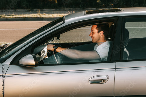 Young attractive caucasian man in white t-shirt sitting in the car © Romvy