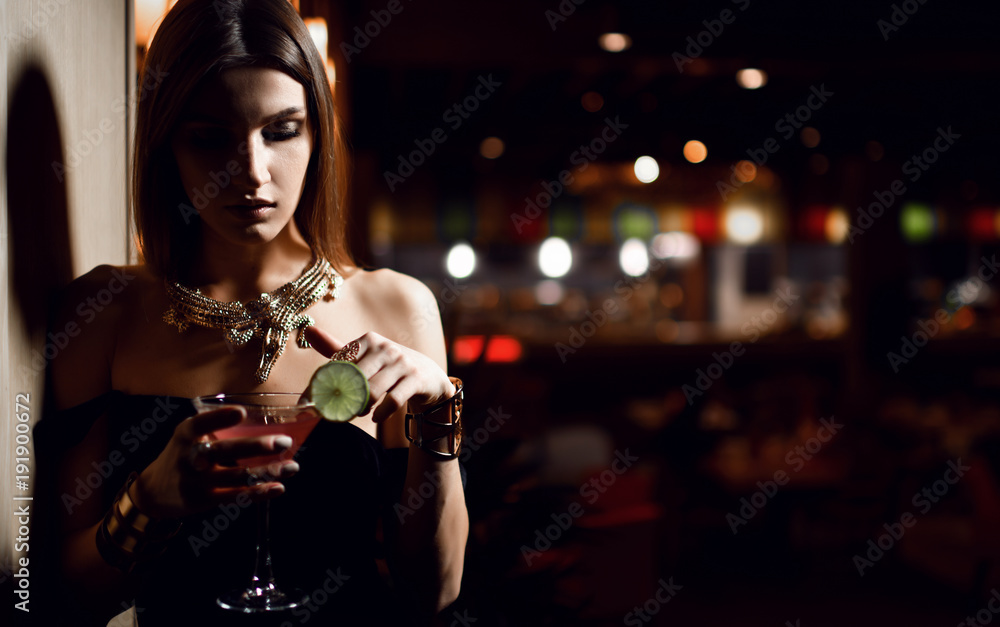 Obraz premium Beautiful sexy fashion brunette woman in expensive interior restaurant relaxing with martini cosmopolitan cocktail 