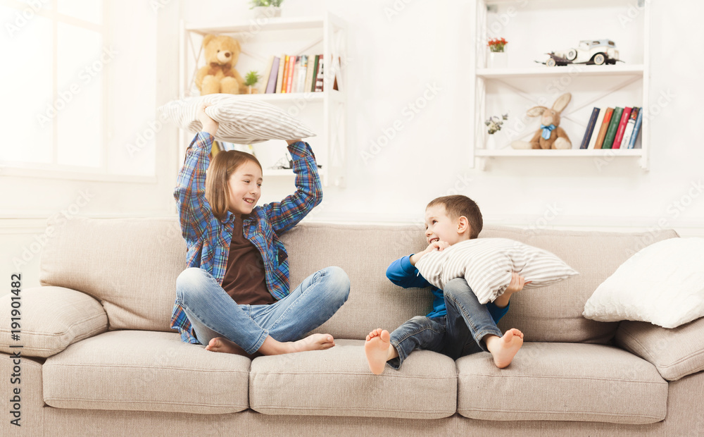 Obraz premium Brother and sister having pillow fight on sofa